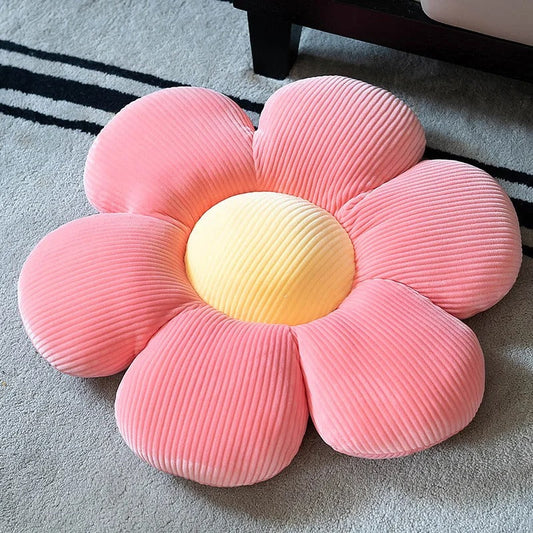 Pink and yellow flower-shaped throw pillow with soft ribbed texture on gray carpet