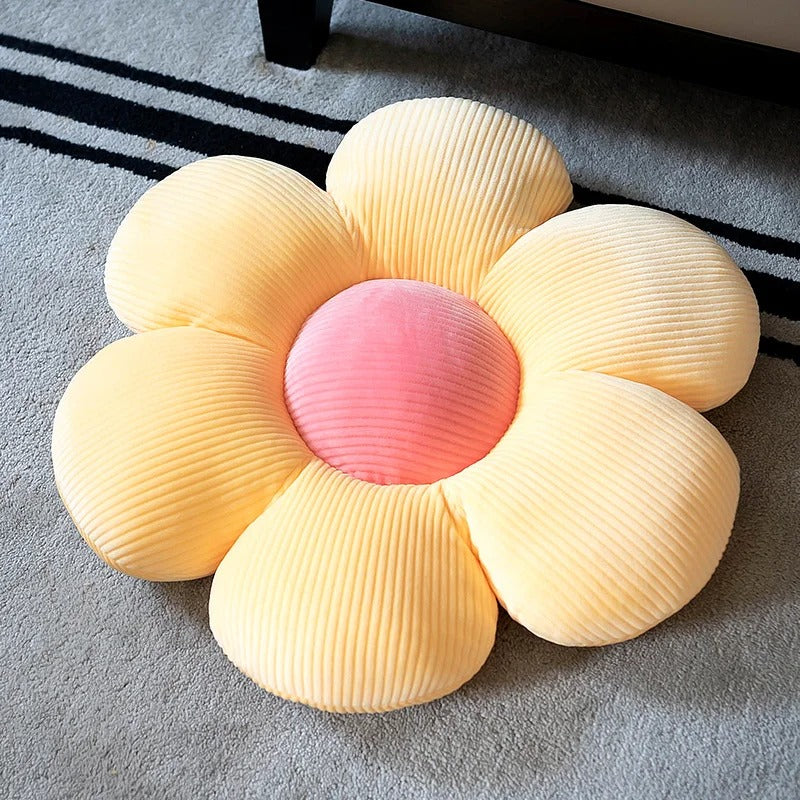 Soft yellow and pink flower-shaped throw pillow with ribbed texture on a gray carpet