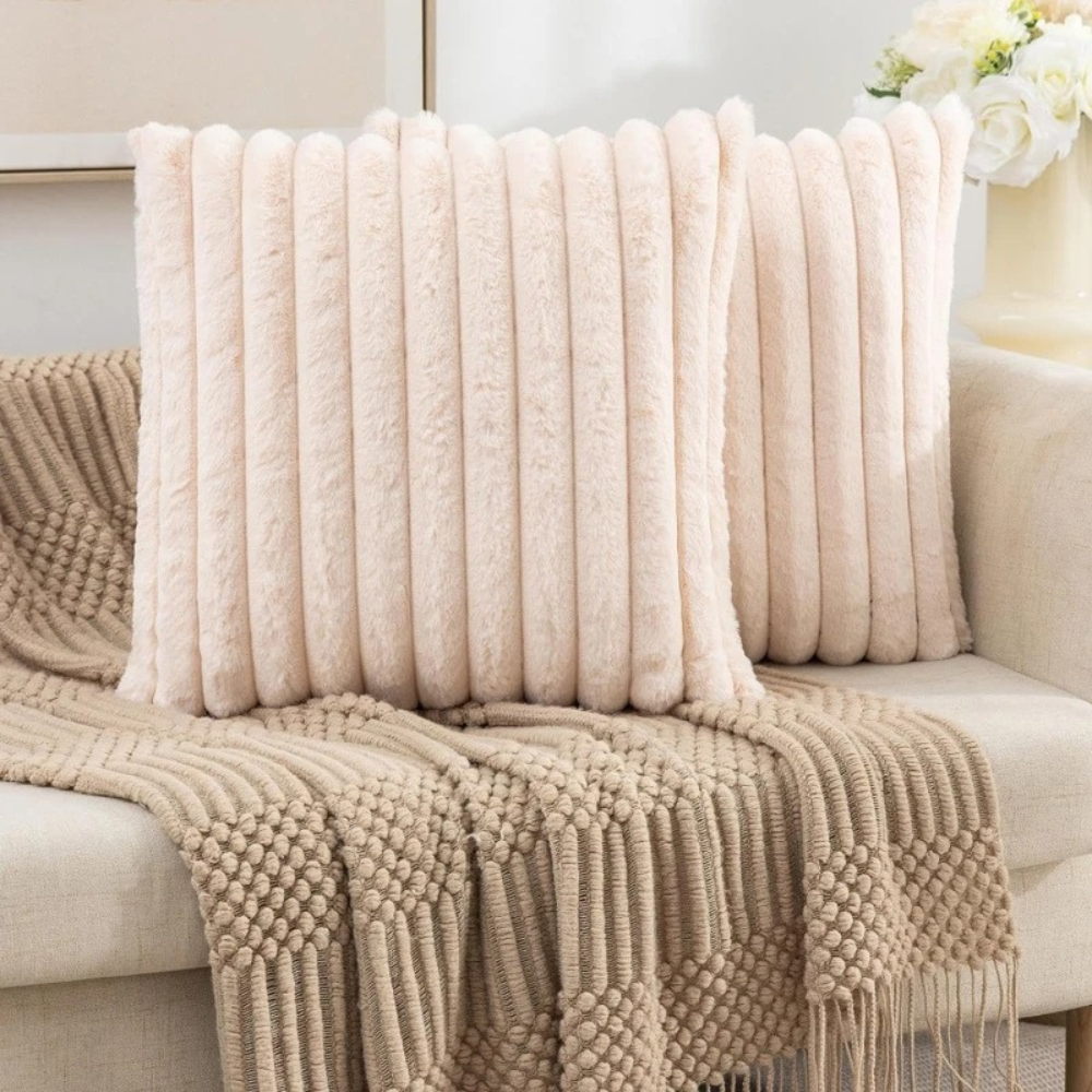 Soft cream colored fluffy throw pillow with vertical ribbed texture on beige couch with knitted throw blanket