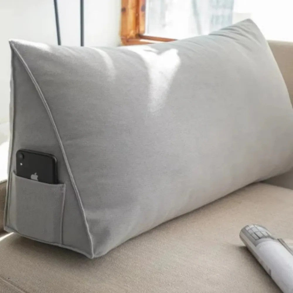 Gray Headboard Pillow Wedge with side pocket holding a smartphone placed on beige sofa
