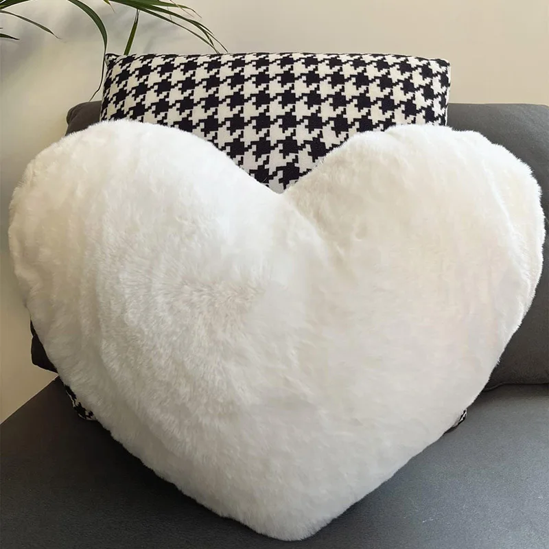 White fluffy heart-shaped throw pillow on black and white houndstooth pillow and gray sofa