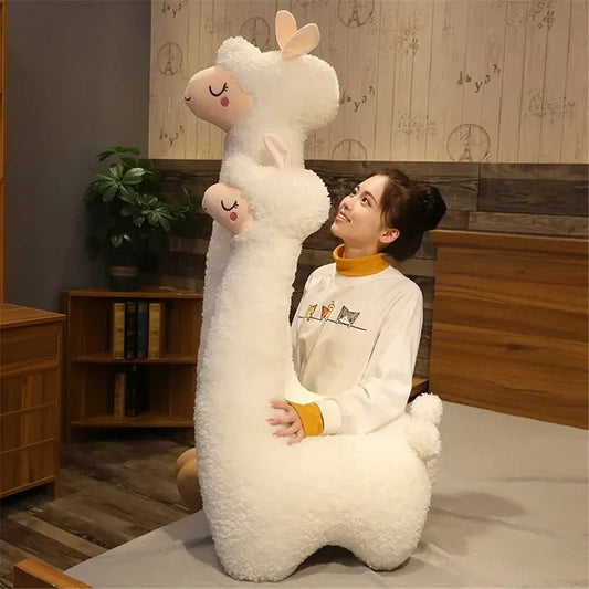 Large plush white llama throw pillow held by woman in cozy room with wooden furniture