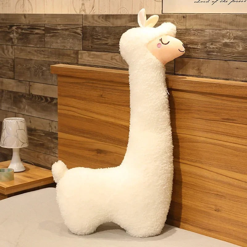Plush white llama shaped throw pillow with soft texture by getblissyneck on bed with wooden headboard
