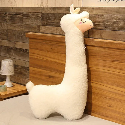 Plush white llama shaped throw pillow with soft texture by getblissyneck on bed with wooden headboard