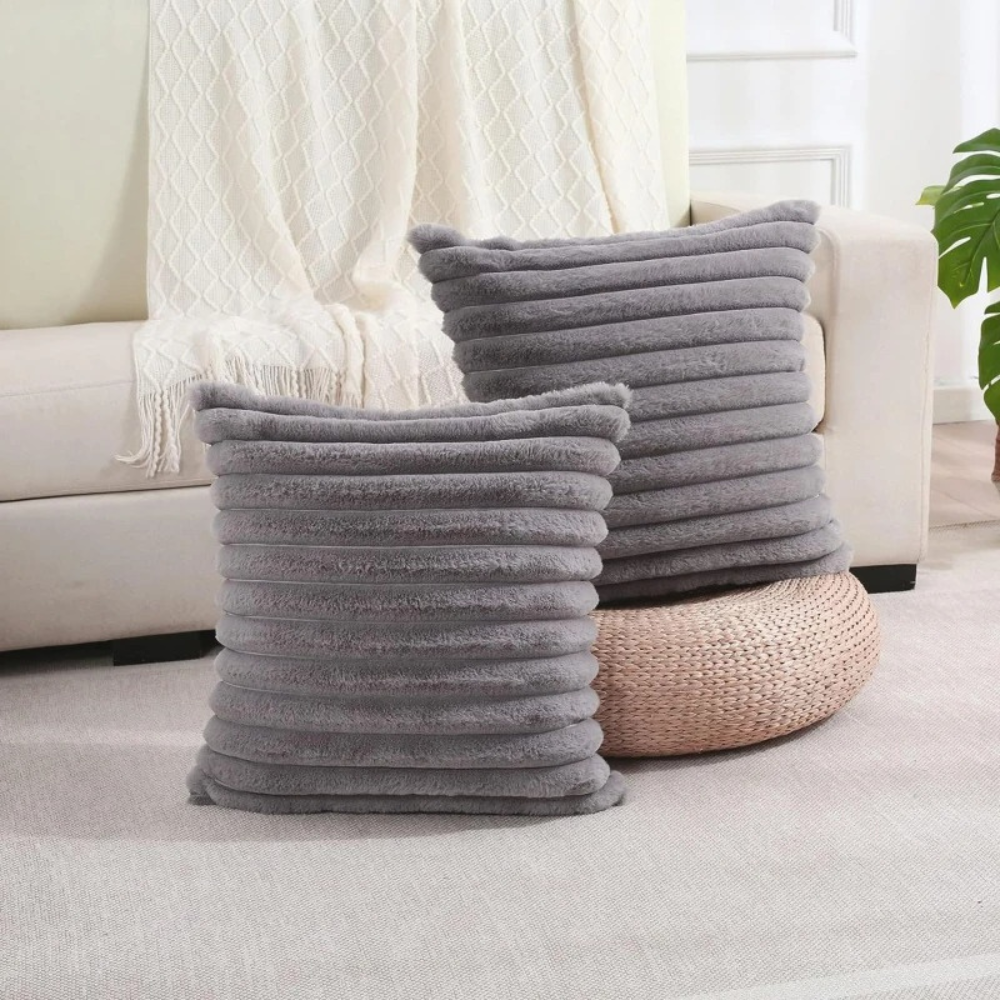 Two soft grey throw pillow grey case with textured horizontal stripes placed in a modern living room