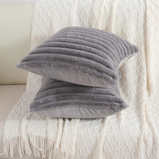 Soft grey throw pillow grey case with ribbed texture placed on a white knitted blanket on sofa