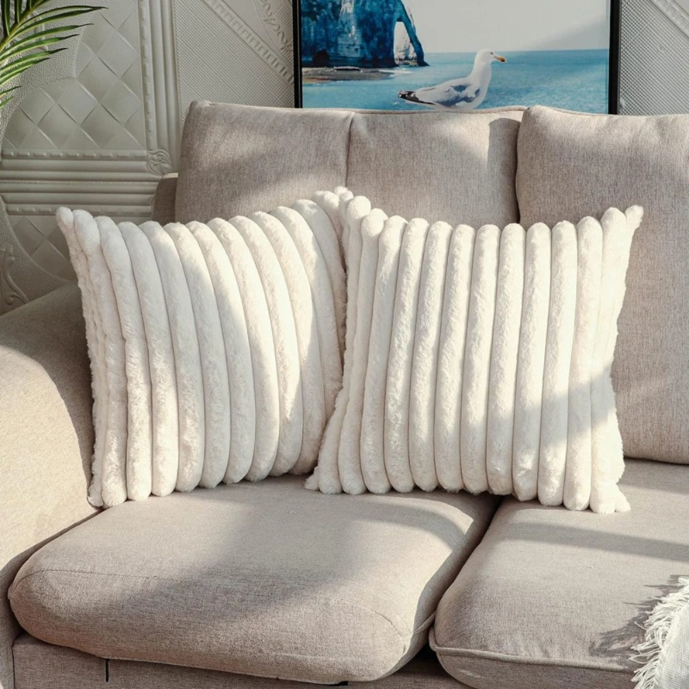 Two textured white throw pillows with vertical ridges on a beige sofa featuring throw pillow white case