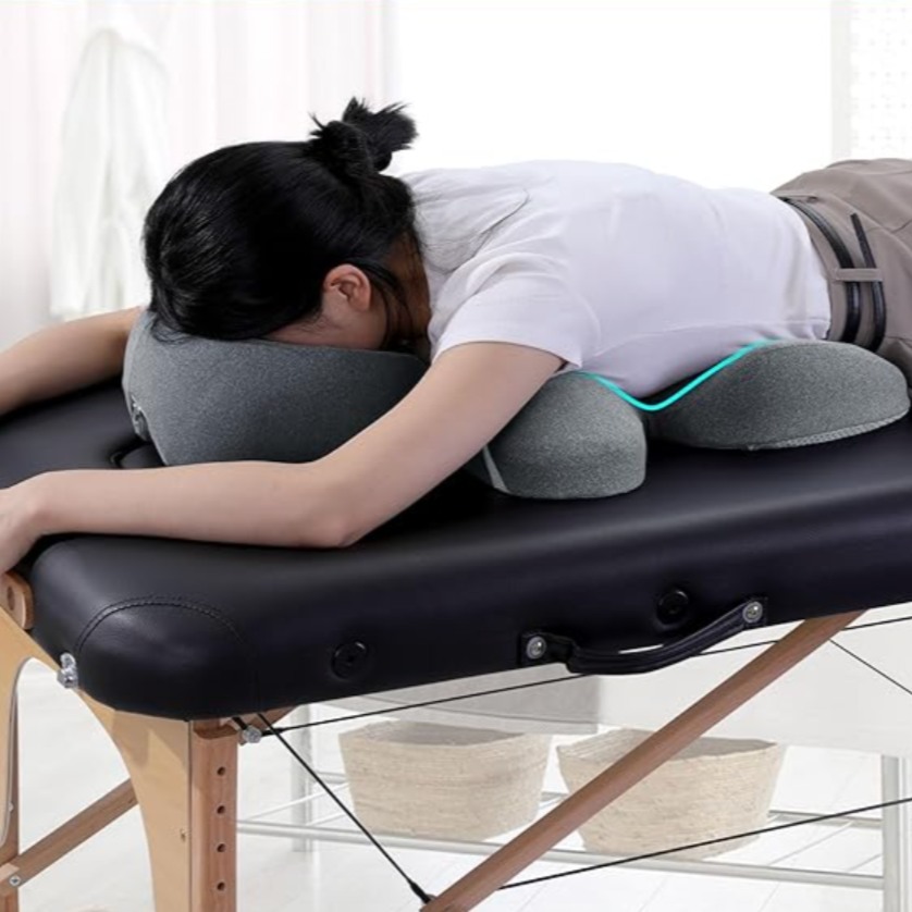 Person lying face down on a massage table using a gray Title Relaxing Pillow 2-in-1 for neck support